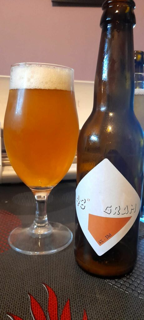 Une bière 48'' GRAM dans un verre à côté de sa bouteille